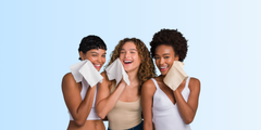Three young women smiling and cleansing their faces.